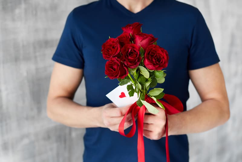 A man holding a bunch of roses and a love letter in his hands