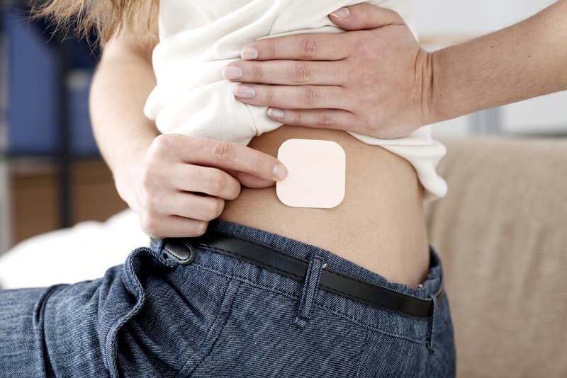 A lady applying a contraceptive patch to her body