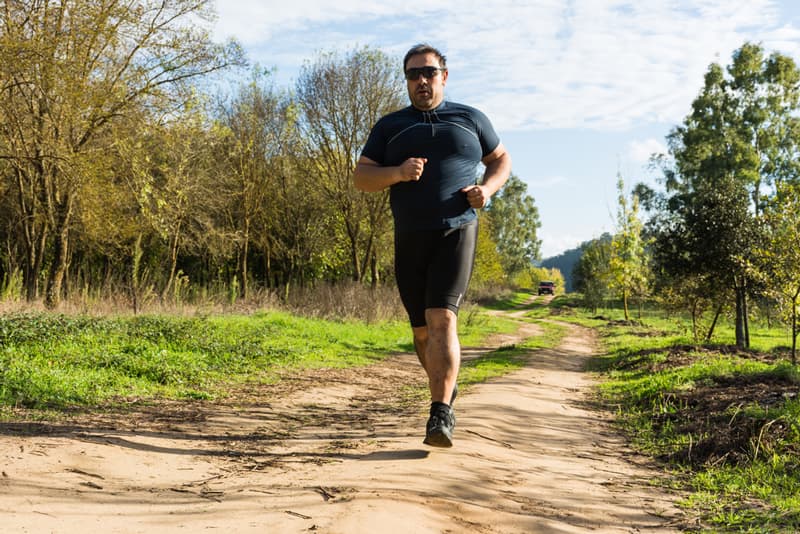 An overweight man running outdoors in an attempt to get fitter and lose some weight