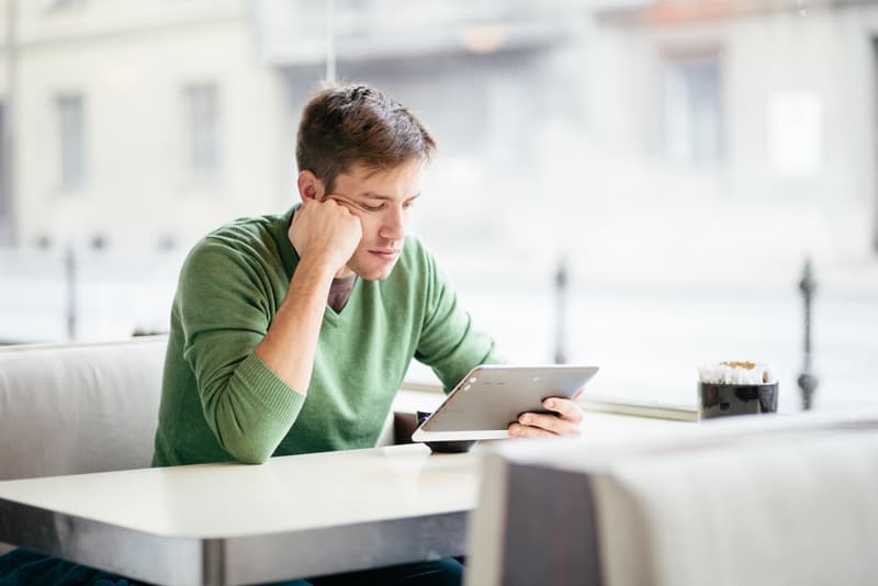 A man looking at his tablet device at a desk