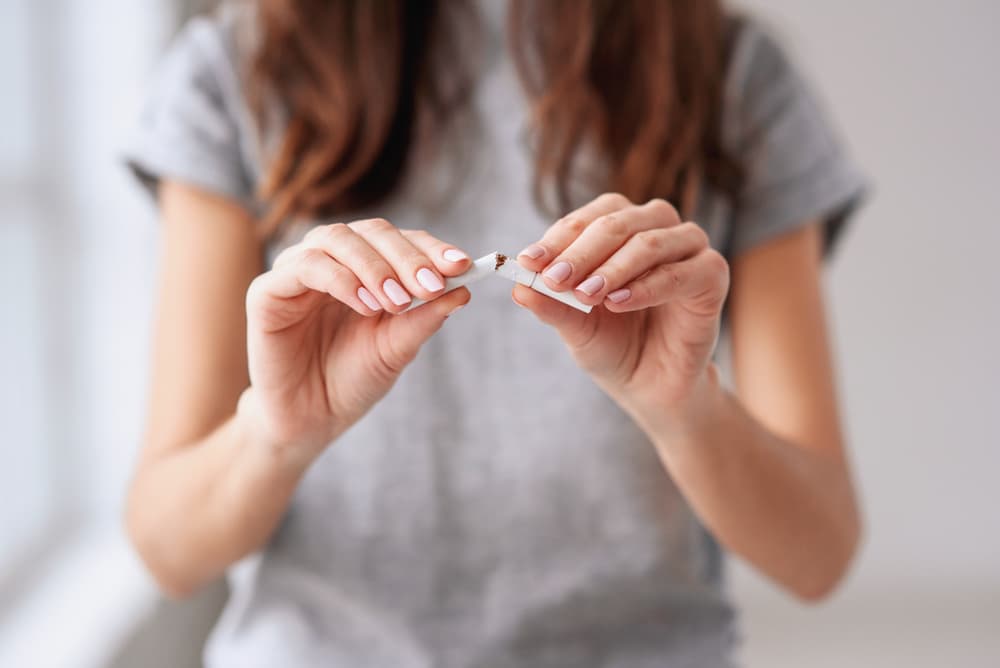 A lady breaking a cigarette in half