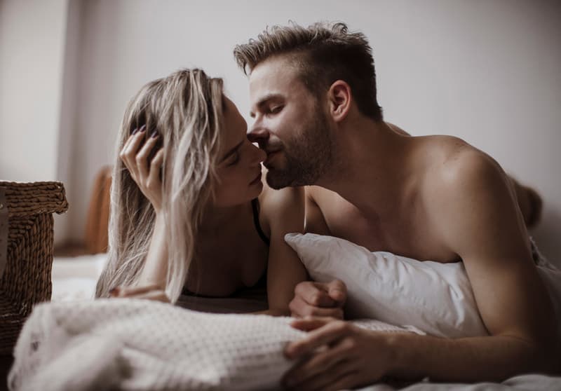 A man and a woman kissing in bed