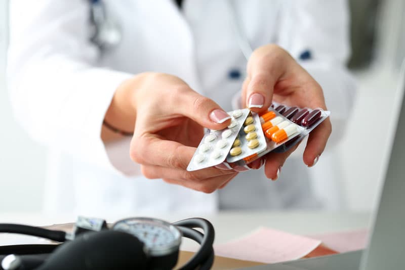 A doctor holding various blister packs of medication in their hand