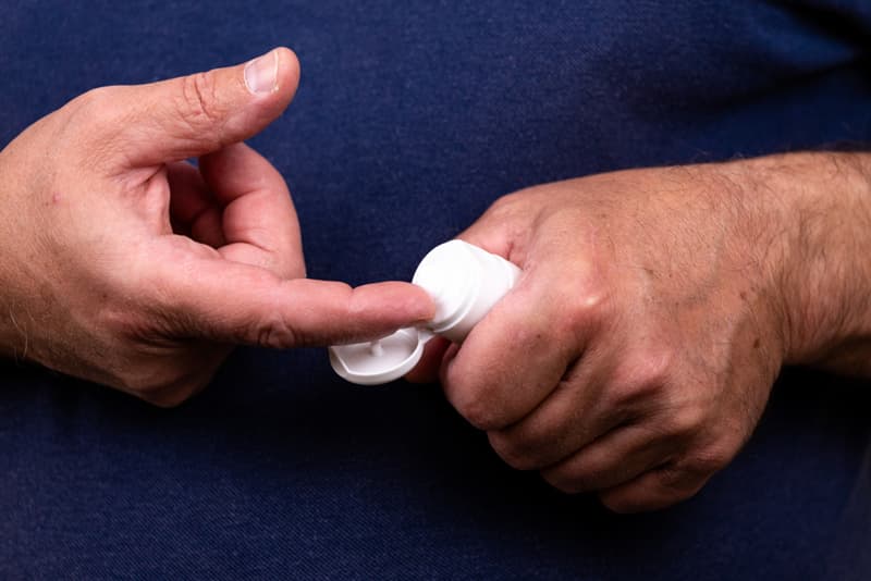 A man applying a thrush treatment cream to his finger