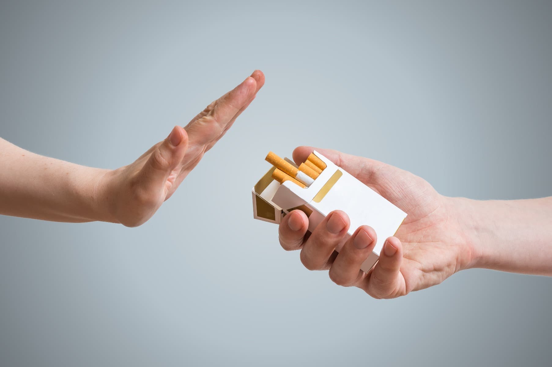 A hand rejecting a packet of cigarettes being offered