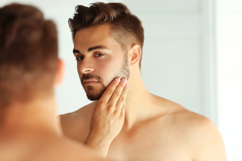 A man touching his acne free face