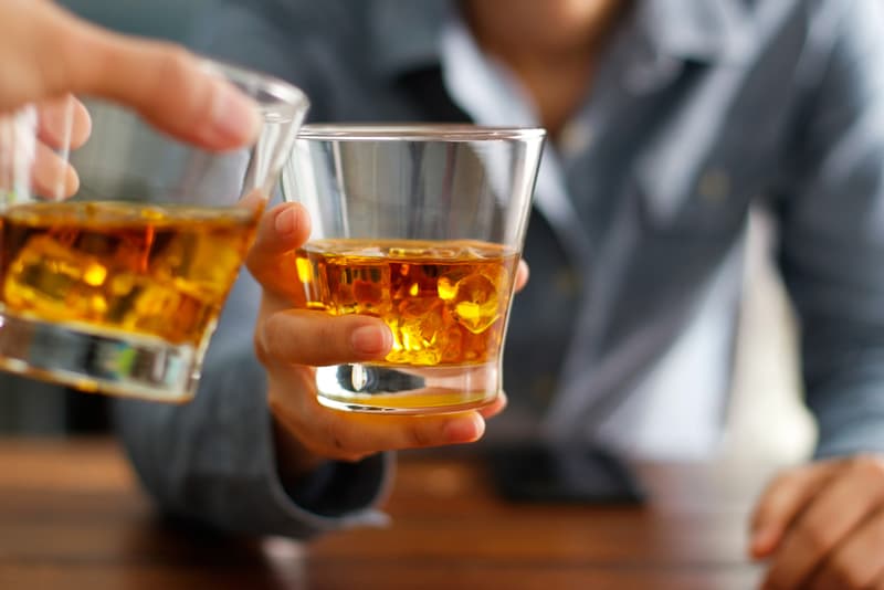 2 glasses of alcohol being touched together in a toast