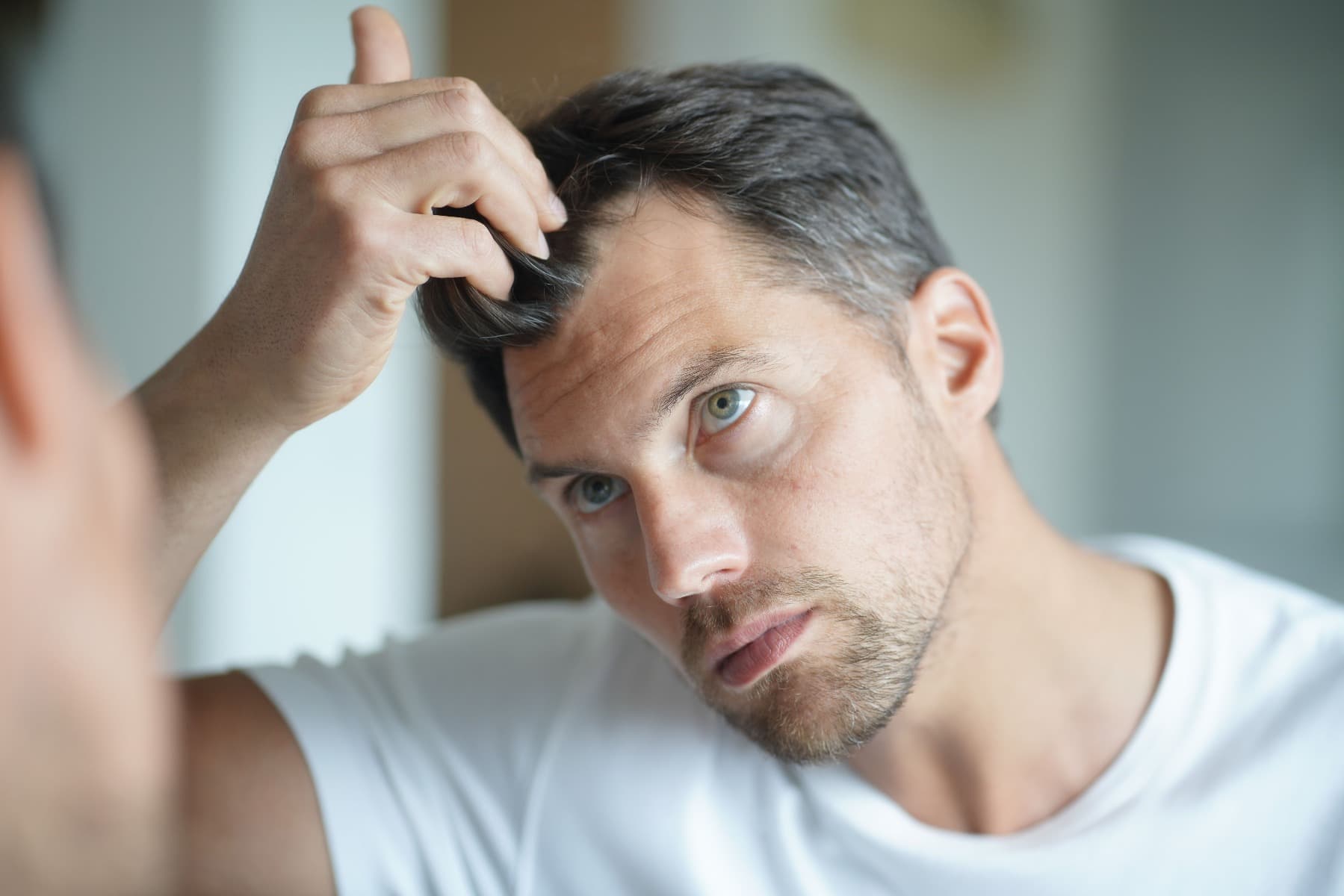 A man assessing his hair loss in the mirror