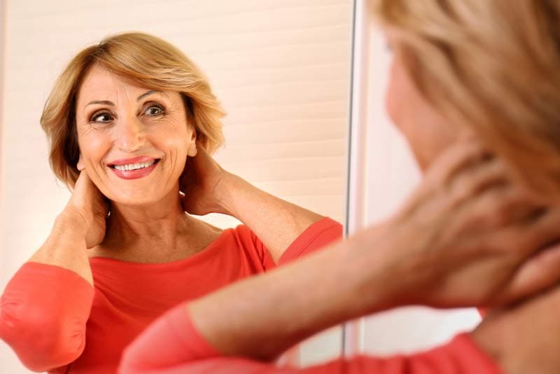 A lady looking in the mirror looking happy