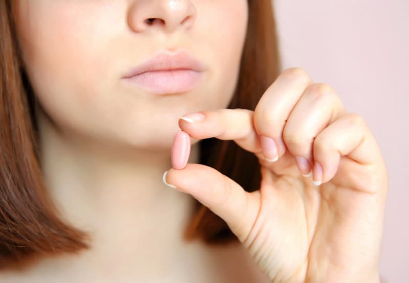 A lady holding the pill