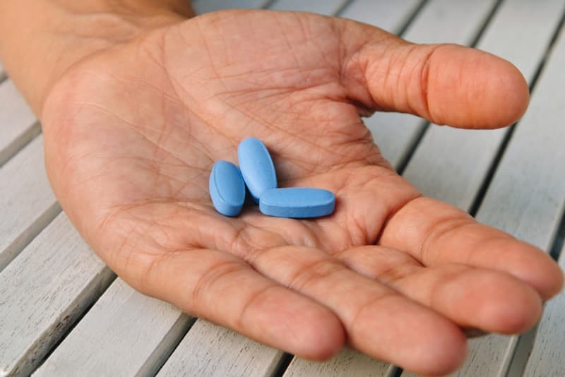 A hand holding multiple Viagra tablets