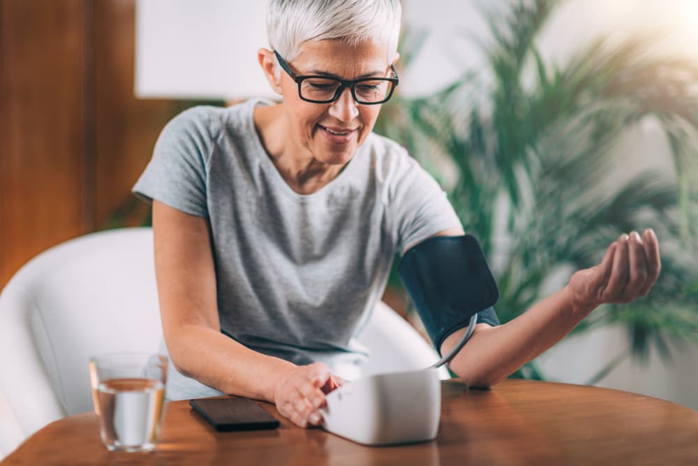 An elderly lady checking her blood pressure on a monitor whilst at home