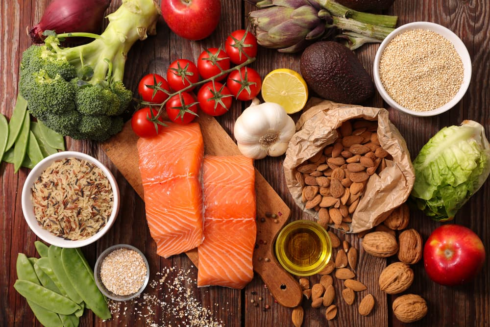 Various food on a table, including vegetables, salmon, nuts and more