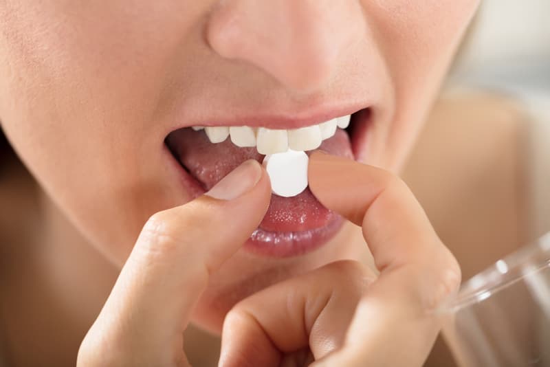 A lady taking a metronidazole tablet