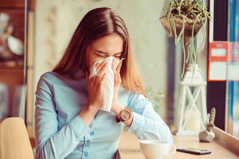 Lady sneezing into a tissue suffering from a common cold