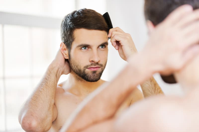 A man combing his hair whilst looking in the mirror
