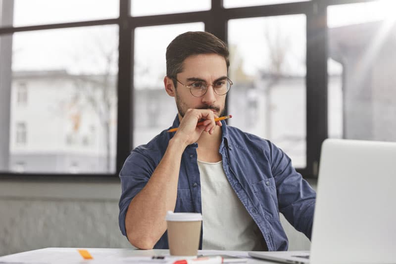 A guy sat at his desk focusing on his work on a laptop