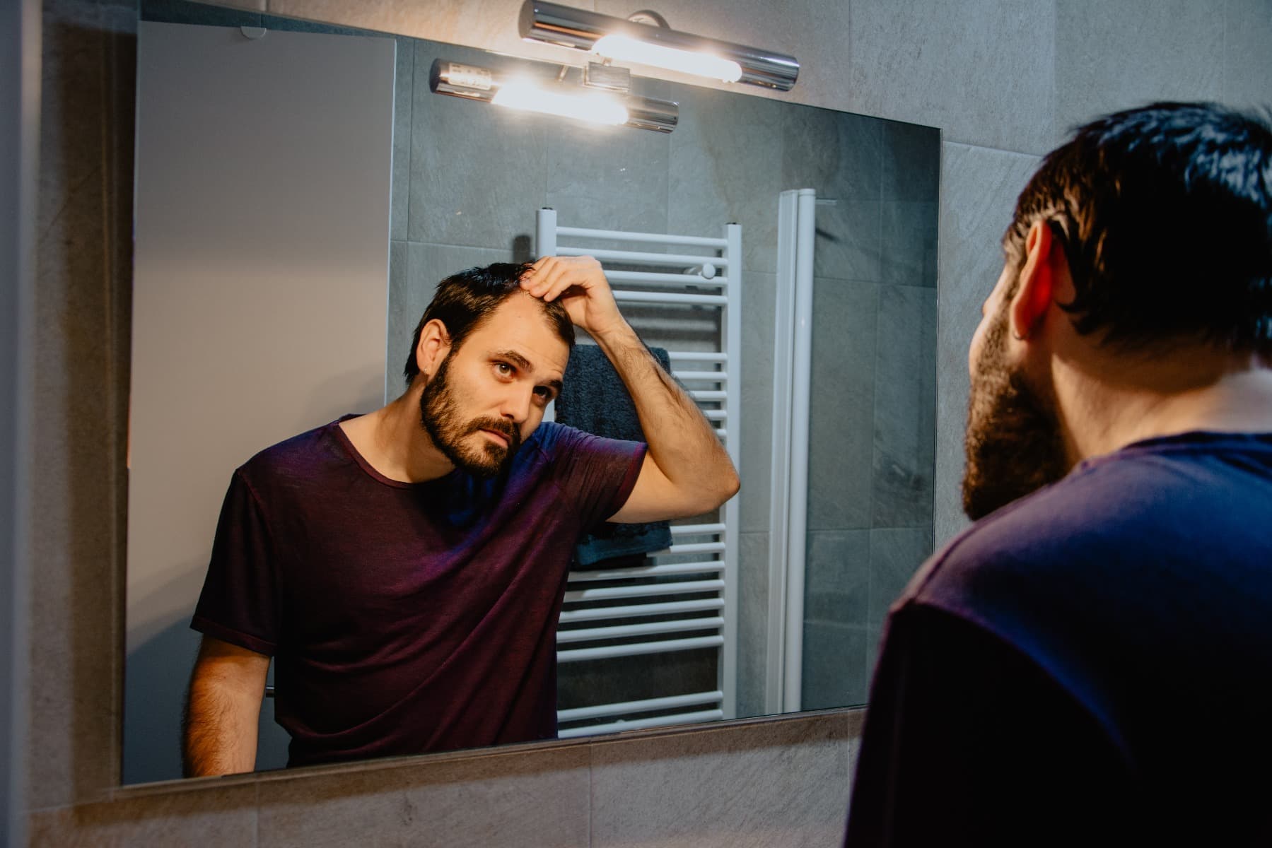 A man assessing his hair loss in the mirror