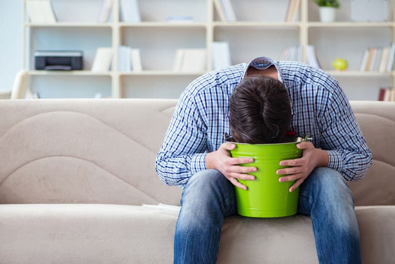 A man vomiting in a bucket