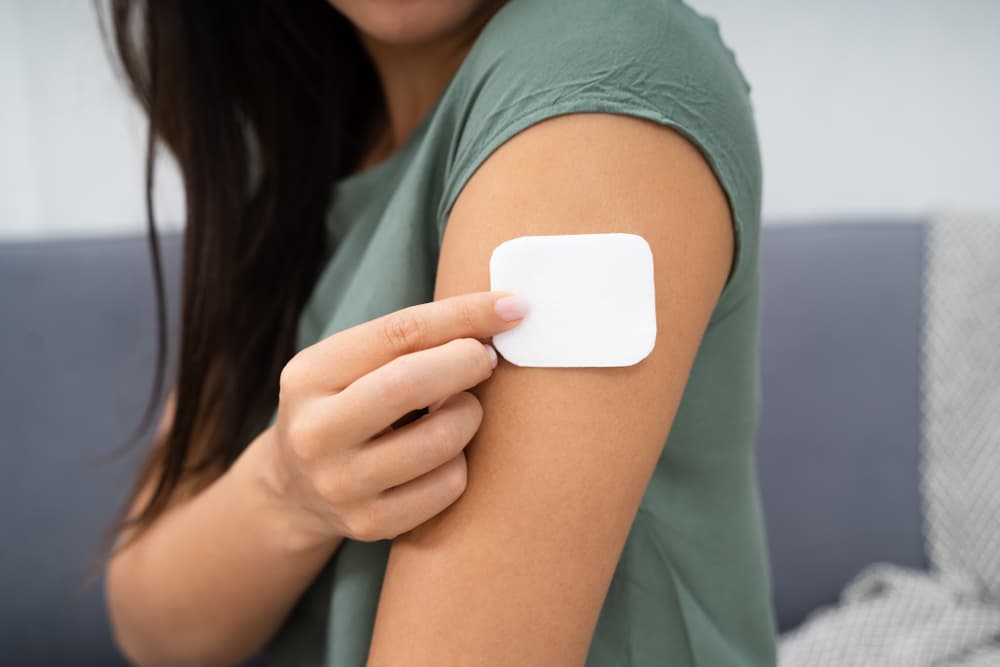 A female applying a HRT patch to her arm