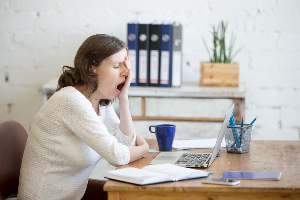 A lady sat at a desk, extremely tired because she has insomnia