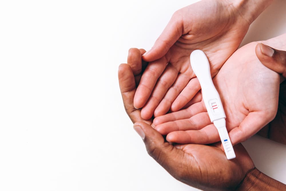 A male and female set of hands holding a fertility test