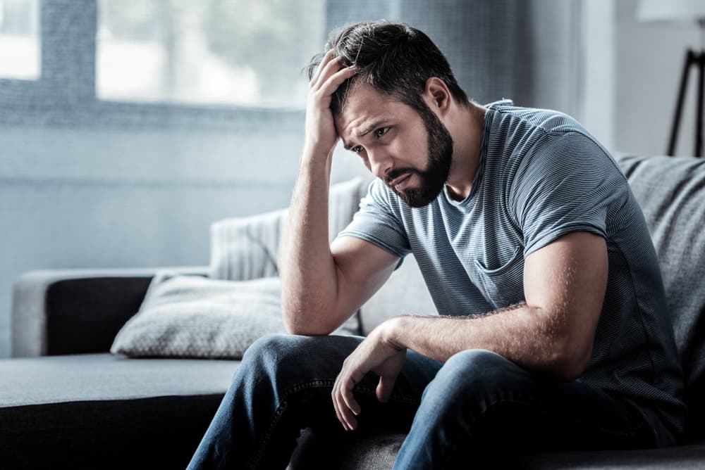 A man sat down looking upset due to experiencing blue balls