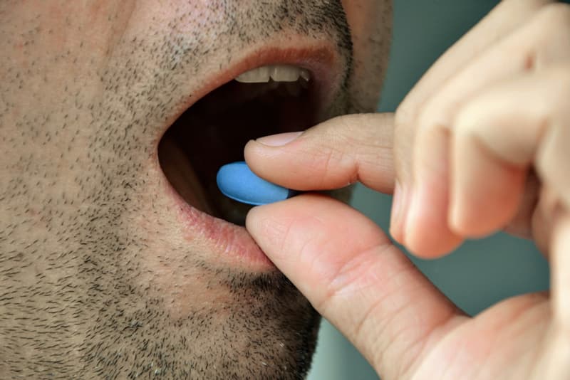 A man placing a Viagra tablet into his mouth