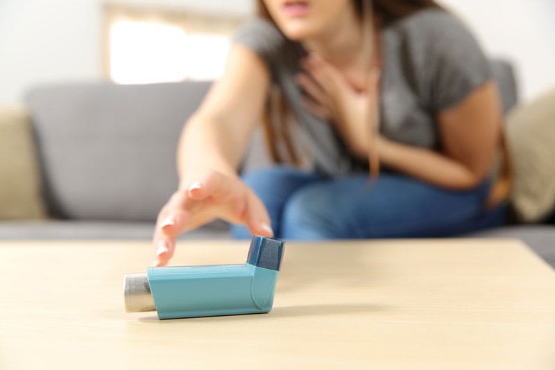 A lady reaching for her Ventolin inhaler as she suffers from an asthma attack