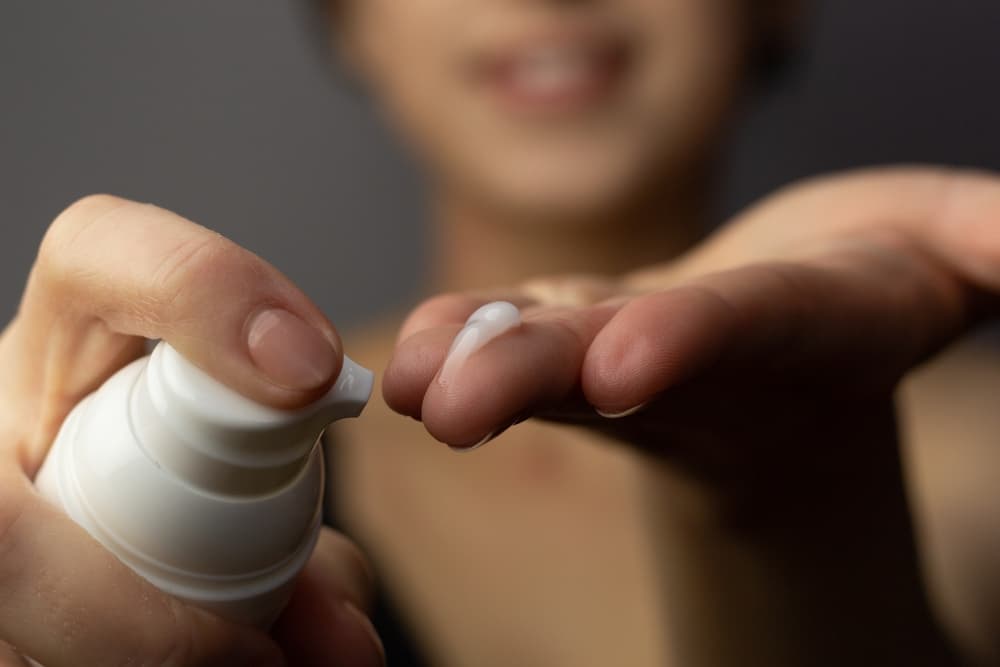 Lady applying Tretinoin cream to her fingertip to add it to her acne