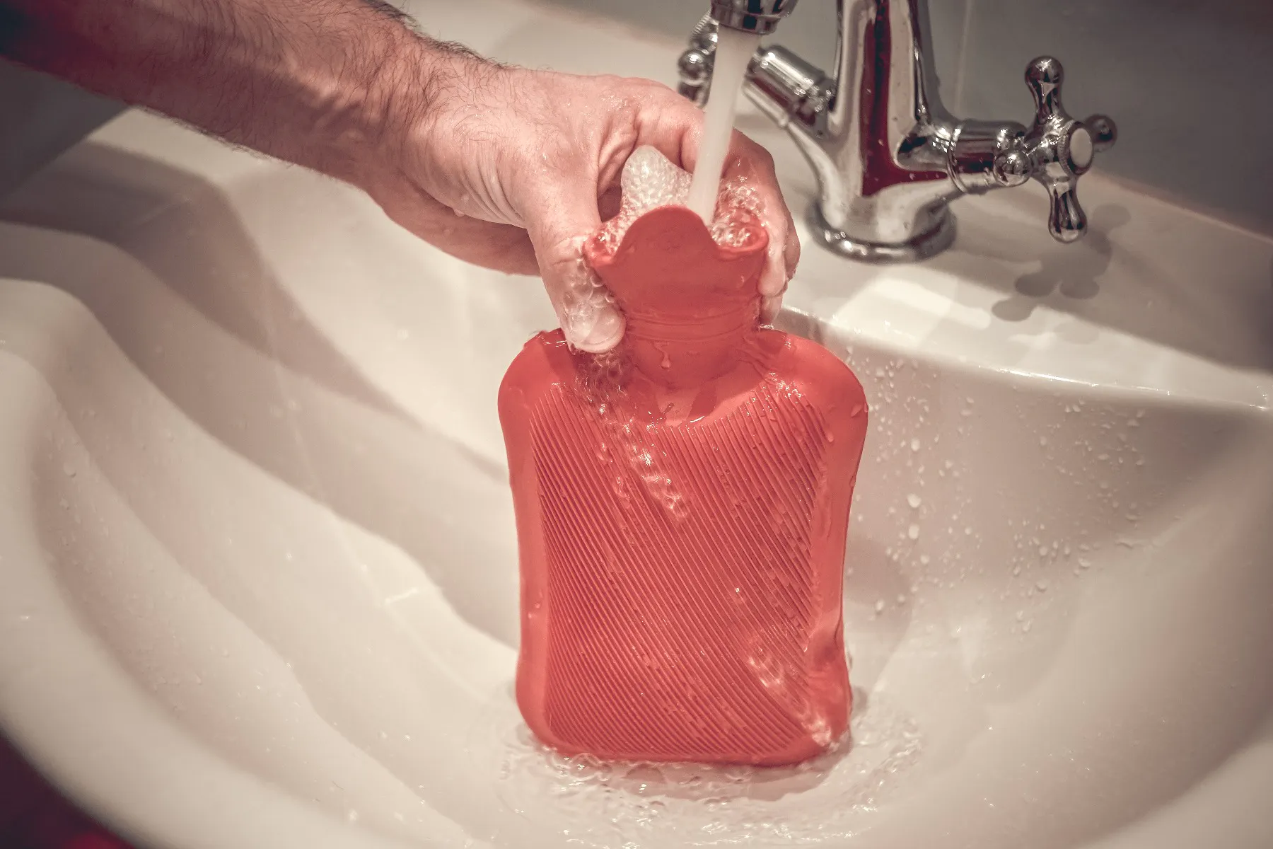 A hot water bottle being filled up in the sink