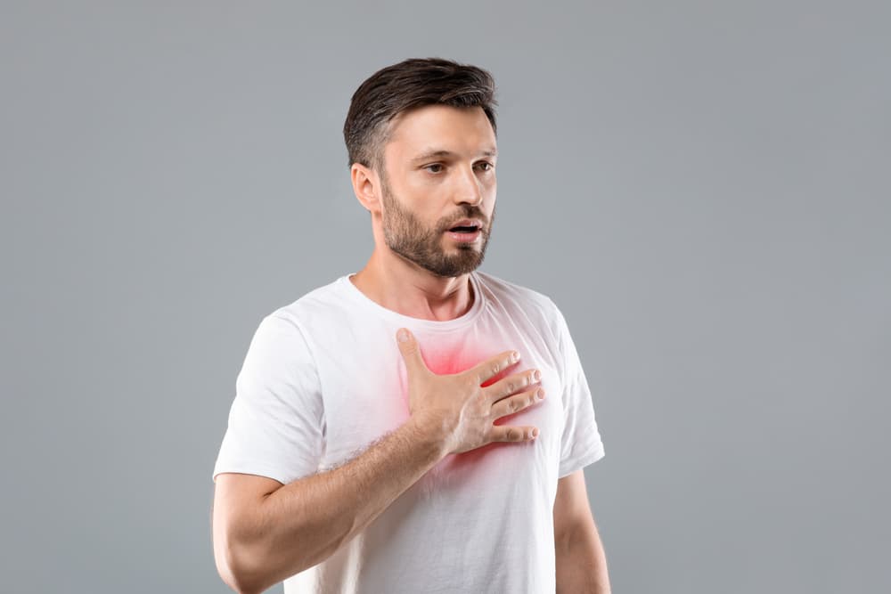 Man clutching his chest as he is suffering from asthma and doesnt have a Ventolin inhaler to help ease her breathing