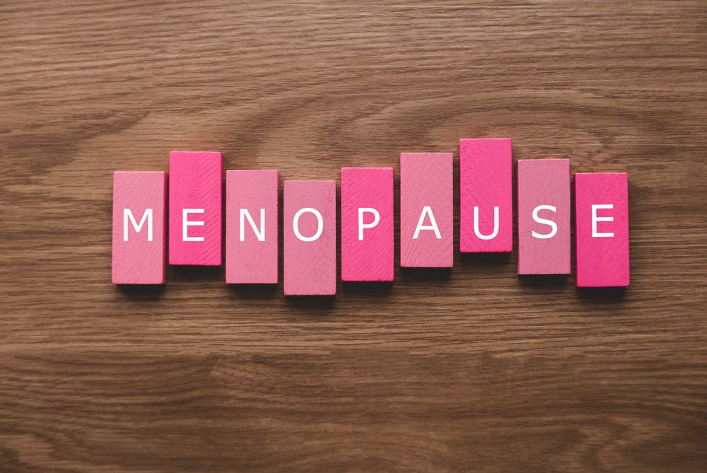 Letters spread across a wooden table that spell out the word 'menopause'