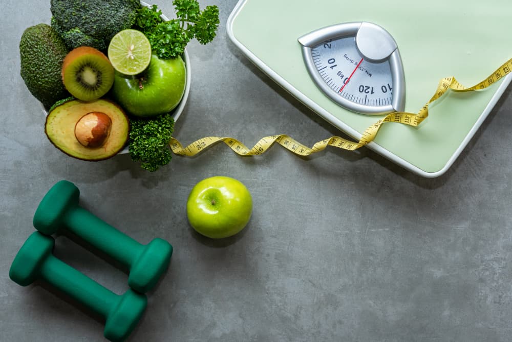 Vegetables next to a set of weighing scale and dumbbells