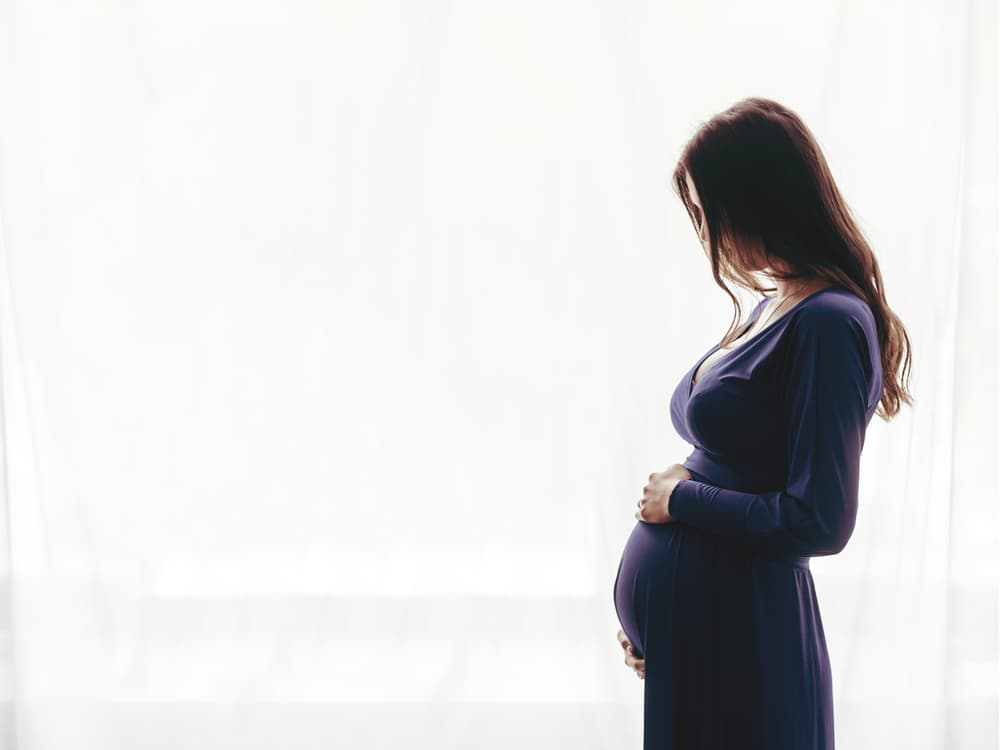 A pregnant lady smiling at her baby bump