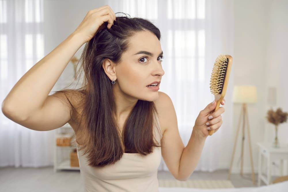 Lady brushing her hair and checking her scalp