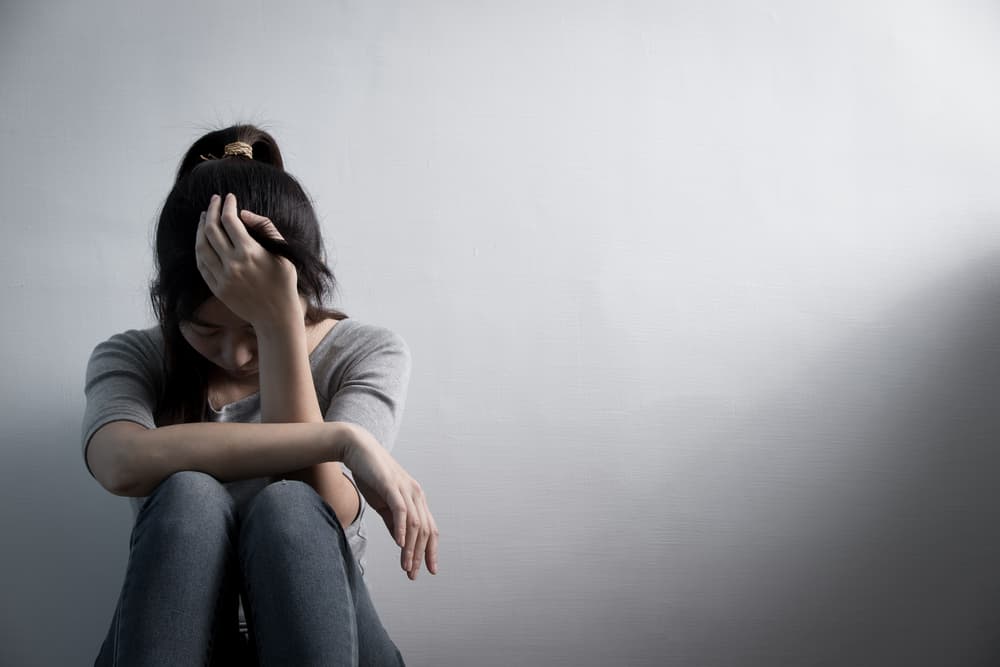 Lady sat on the ground with her head in hear hands due to depression