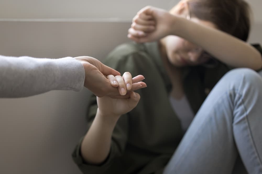 Lady reaching out to an outstretched hand because she needs support with coping with her depression