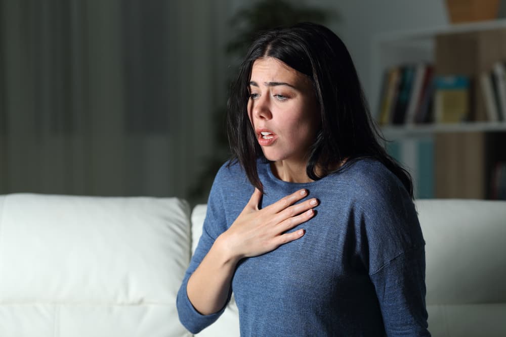 Woman desperately clutching her chest as she is experiencing asthma and anxiety