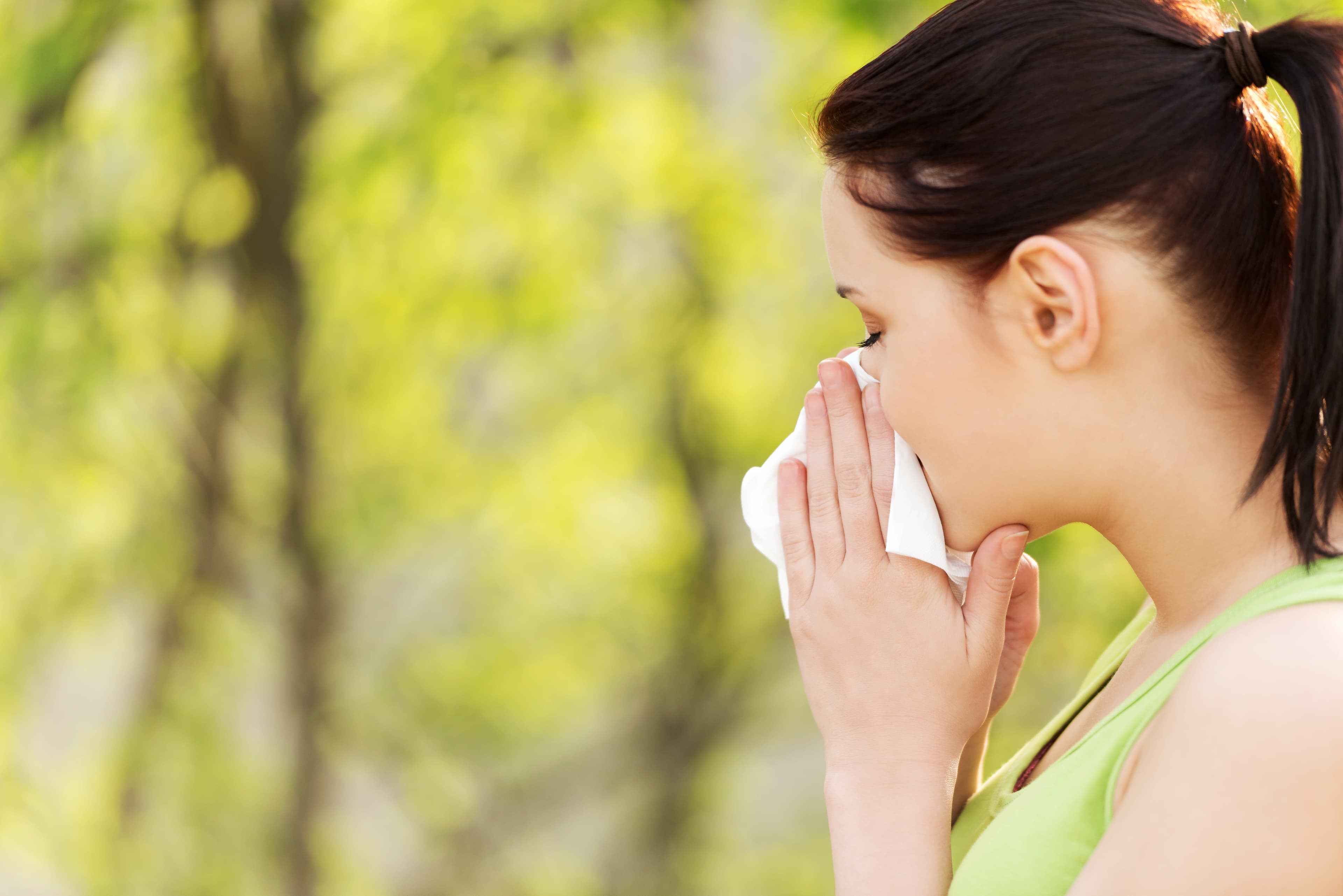 Lady holding tissue to her nose because she has hay fever