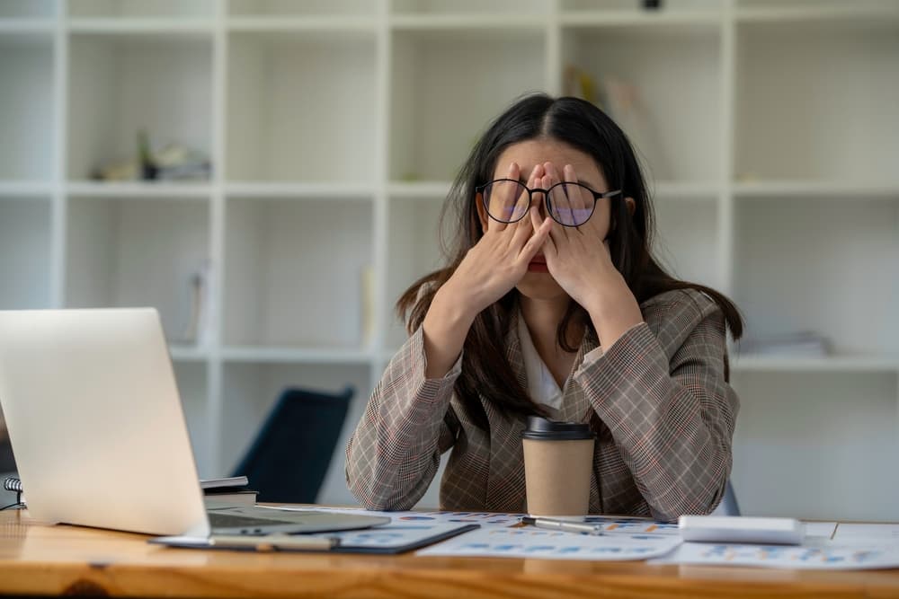 A lady feeling stressed at work whilst being sat at her desk