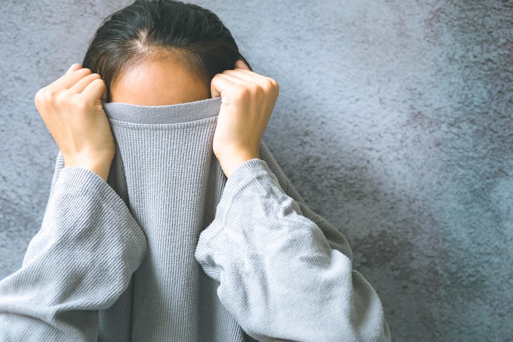 A lady hiding her face under her top because she is experiencing a phobia