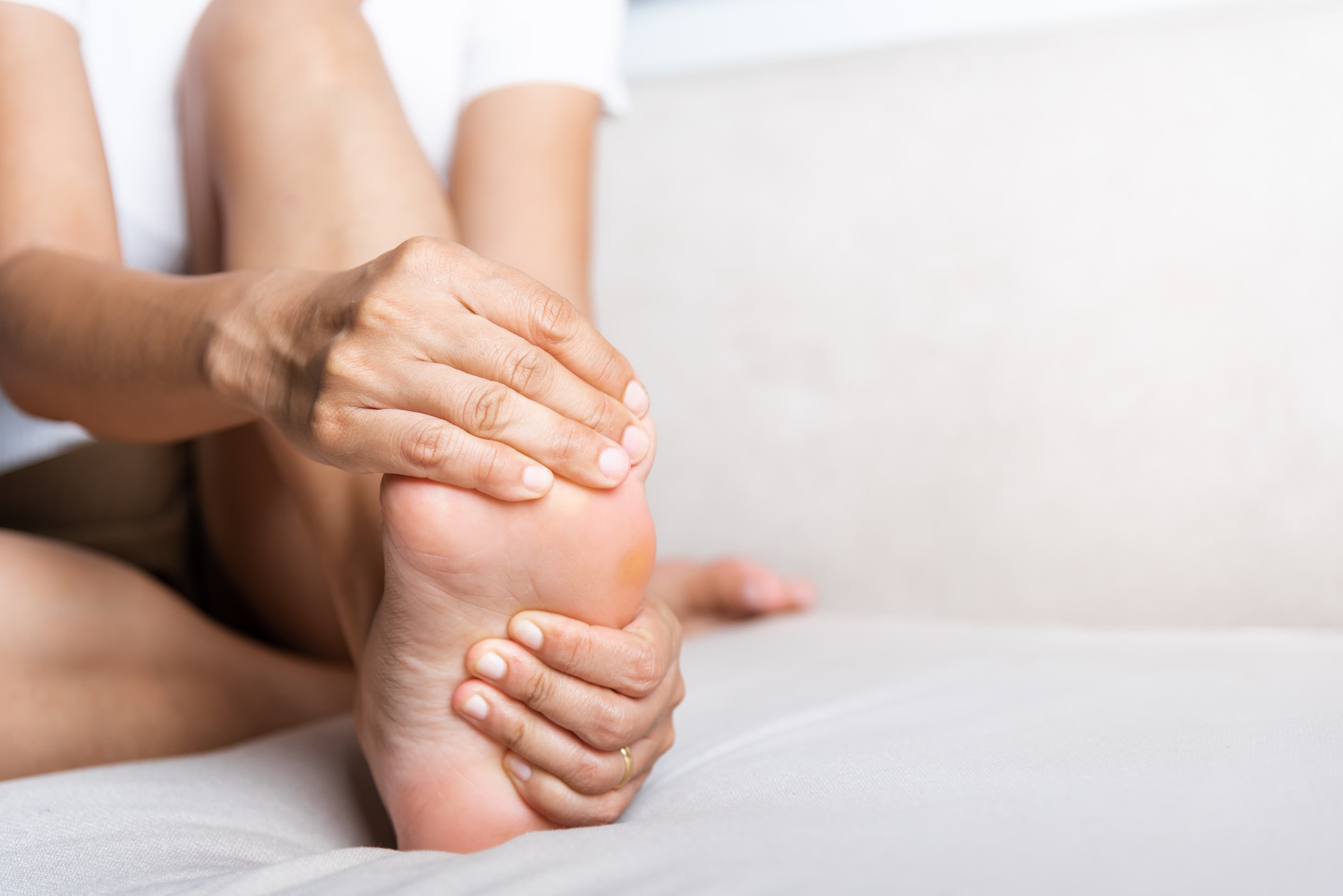 A lady clutching her foot because of experiencing pain from a verruca