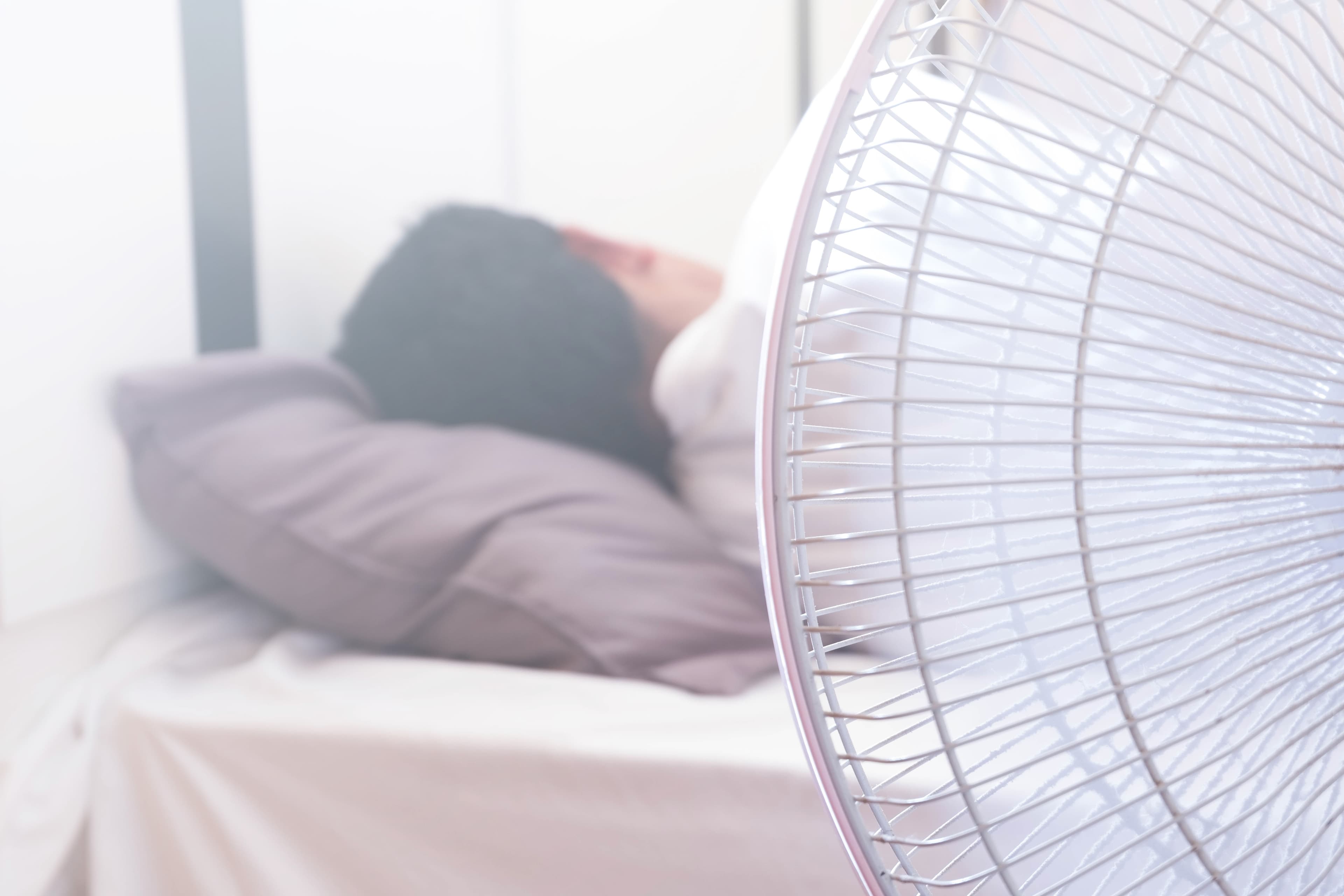 Lady sleeping in bed with the fan on in hot weather