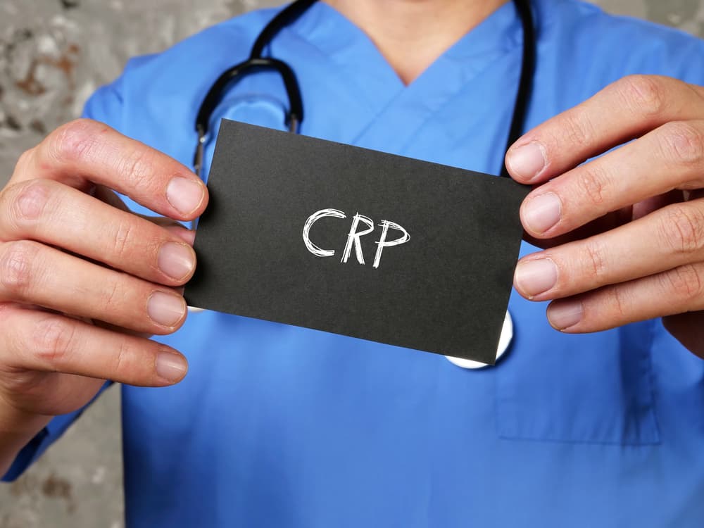 A doctor holding up a sign that has the acronym "CRP" on it