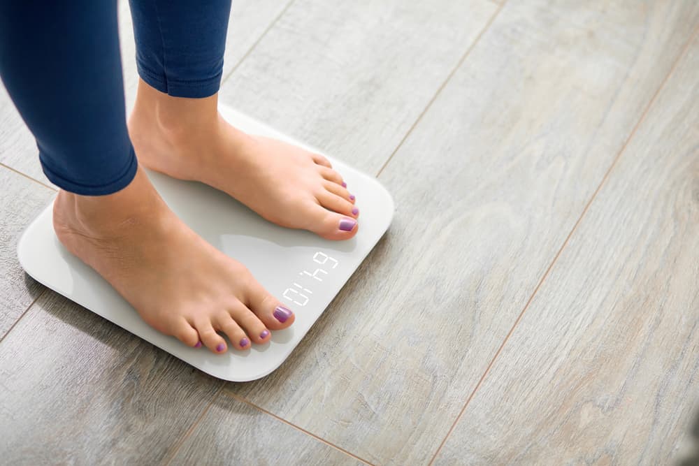 A lady standing on some digital weighing scales to check her body weight#