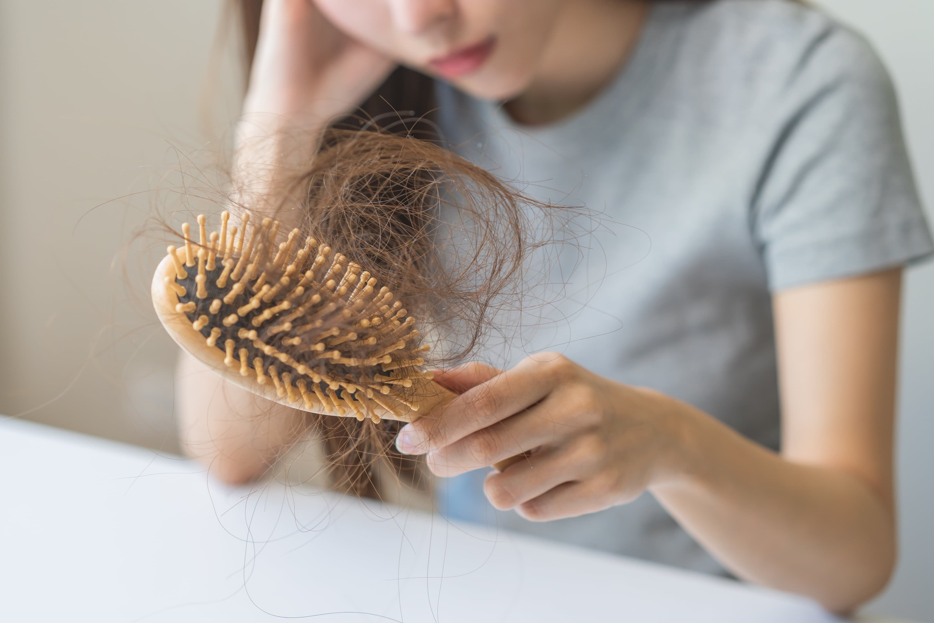 A lady holding a comb which has a lot of hairs on it