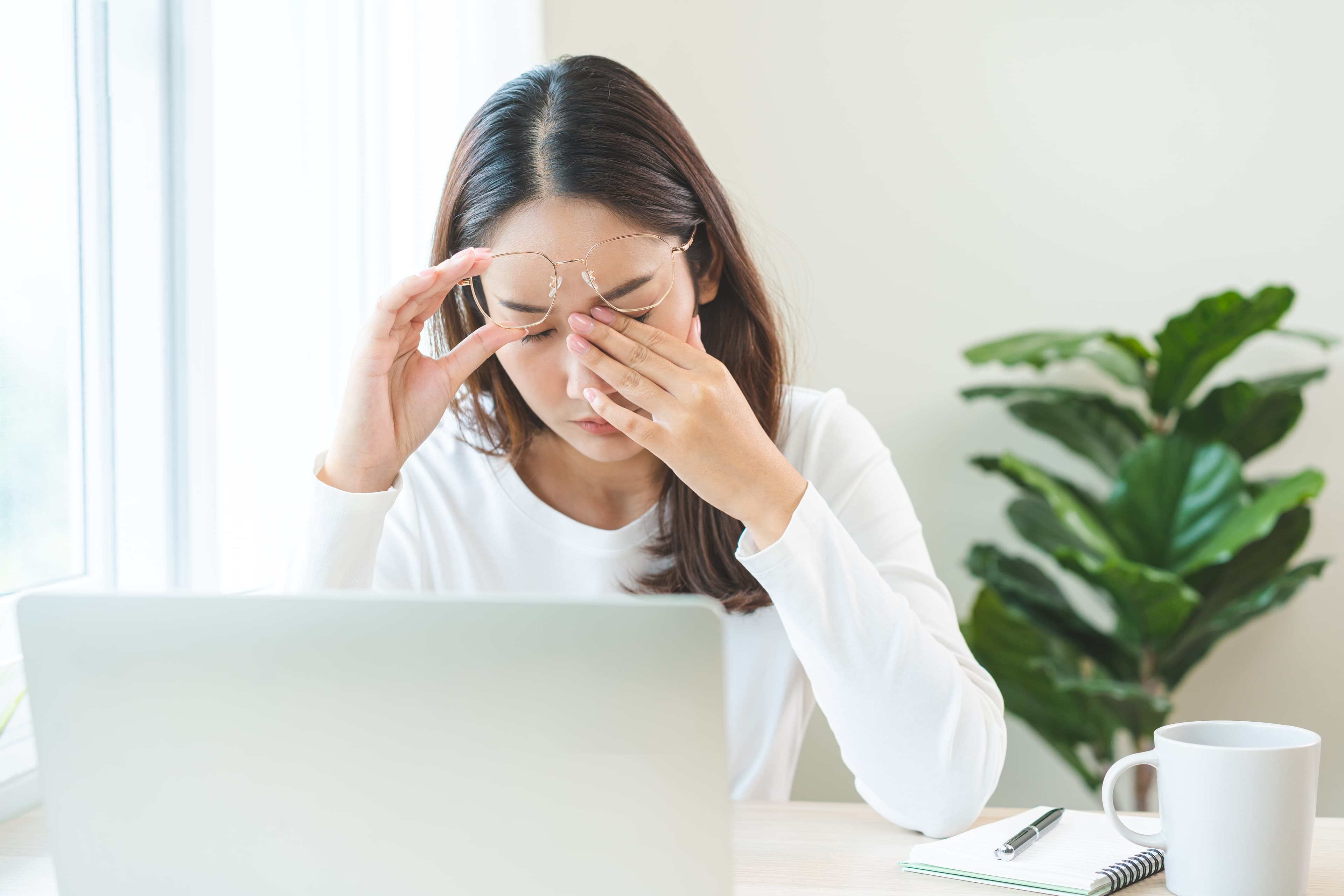 A lady suffering from a migraine at her workdesk